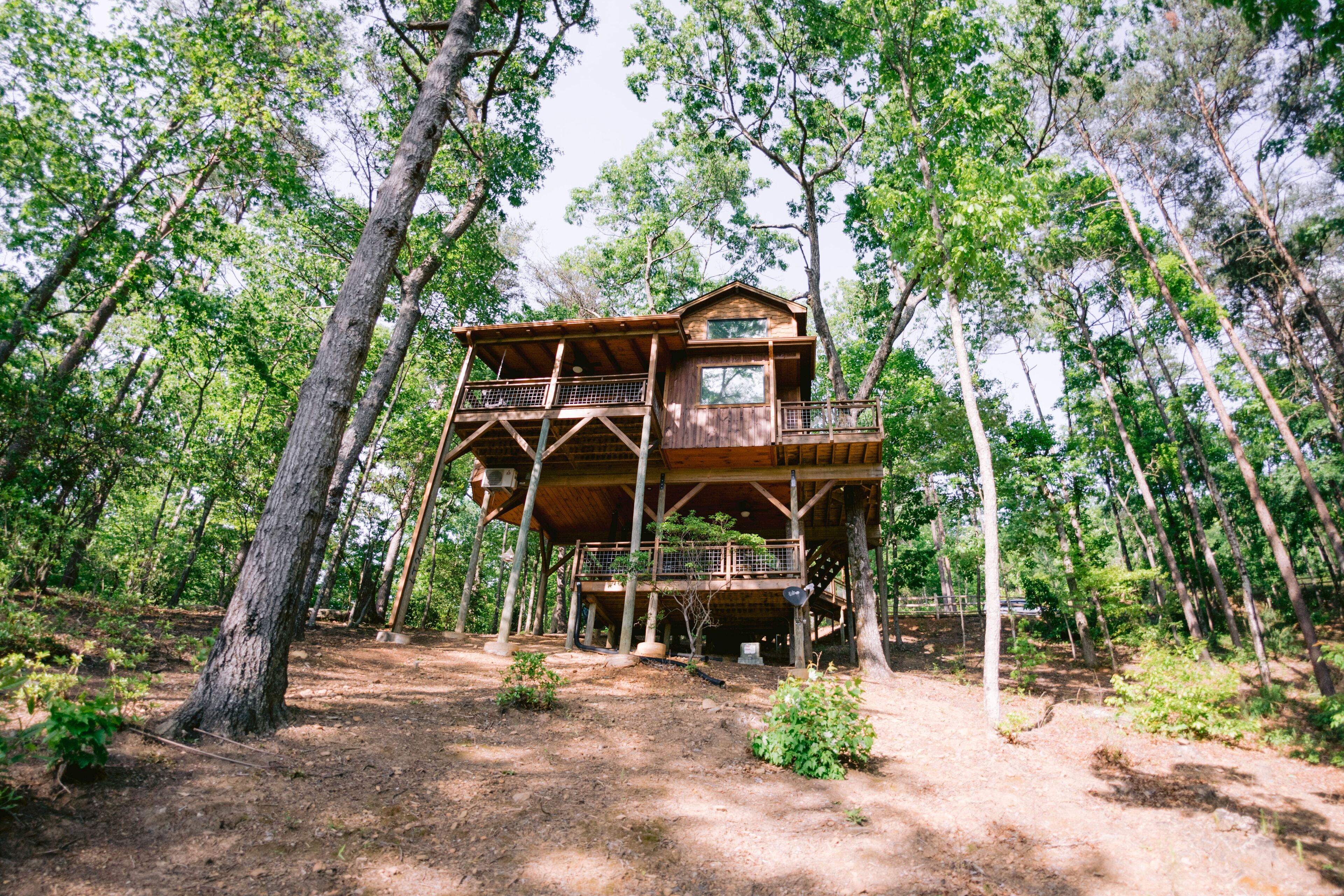 A wooden cabin with a balcony, surrounded by trees.