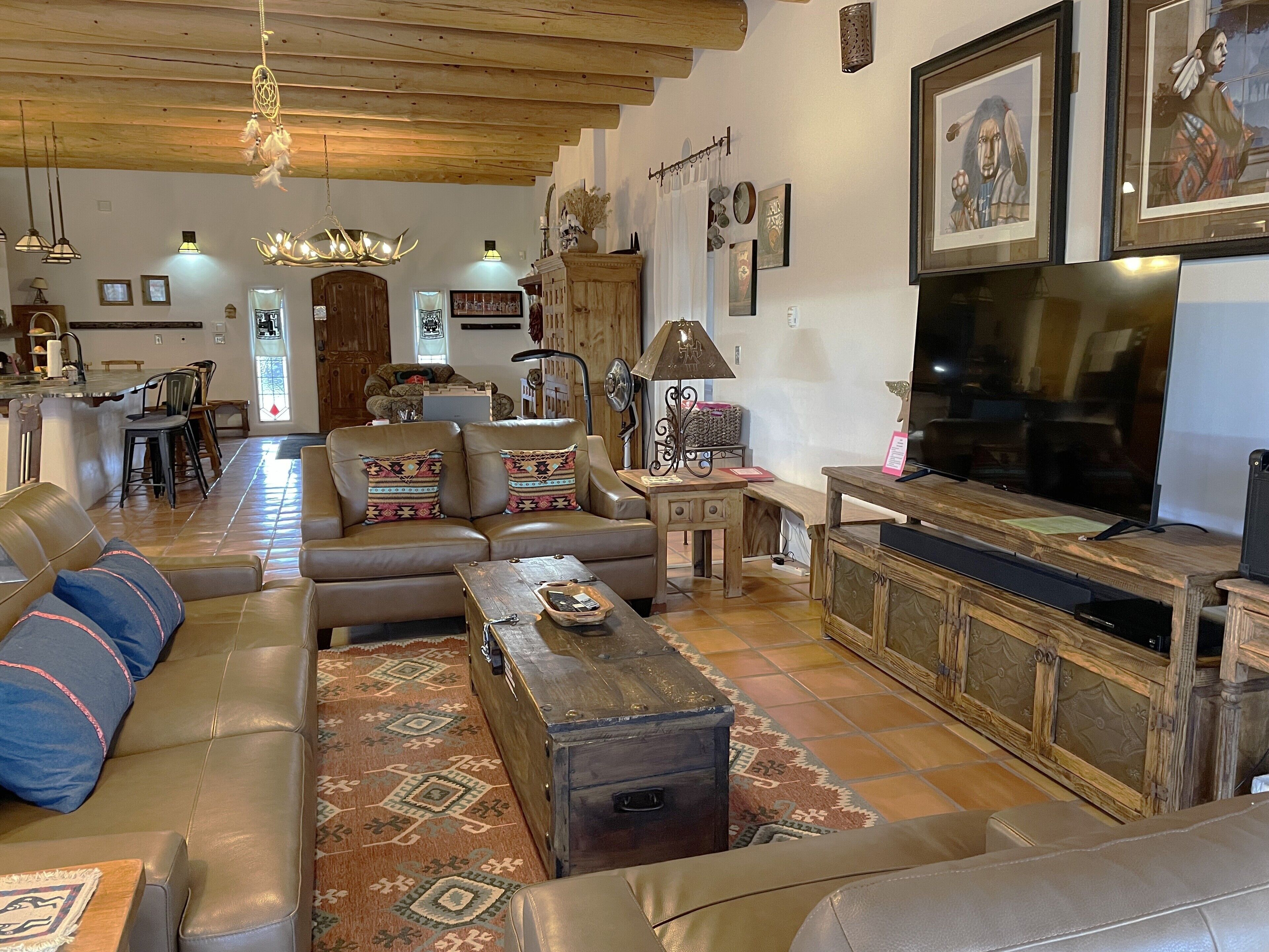A cozy living room with leather sofas, a wooden coffee table, a TV, and a fireplace.