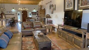 A cozy living room with leather sofas, a wooden coffee table, a TV, and a fireplace.