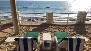 A beach with two lounge chairs and a small table, a palm tree, and a view of the ocean. - BEACHFRONT on a Budget! ~ Condo Sereno ~ Low Beachfront Rate! (BUCERIAS)