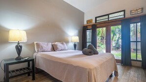 Una camera da letto con un letto, due comodini, una finestra con tende e vista sul verde.