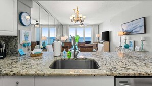 Una cocina moderna con una isla grande, un comedor con vistas y una sala de estar con televisor y obras de arte.