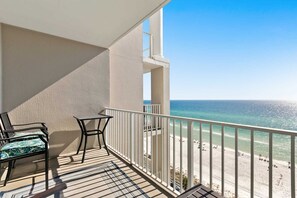 Ein Balkon mit Blick auf den Strand, ein Stuhl und ein kleiner Tisch.