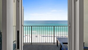 Un balcón con vista a la playa, una barandilla y una puerta.