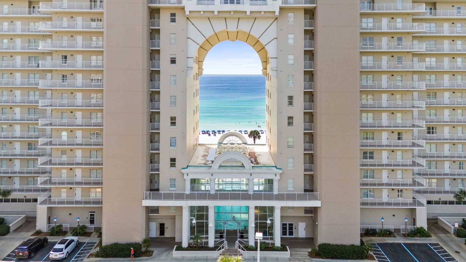 Ett högt hotell med en central atriumgård som leder vidare till en plats med utsikt över stranden.