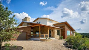 Una casa moderna con fachada de piedra, vigas de madera y porche cubierto.