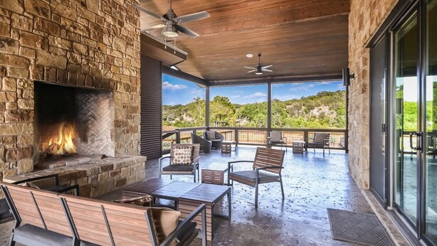 Un patio exterior con chimenea de piedra, asientos y vistas del paisaje.