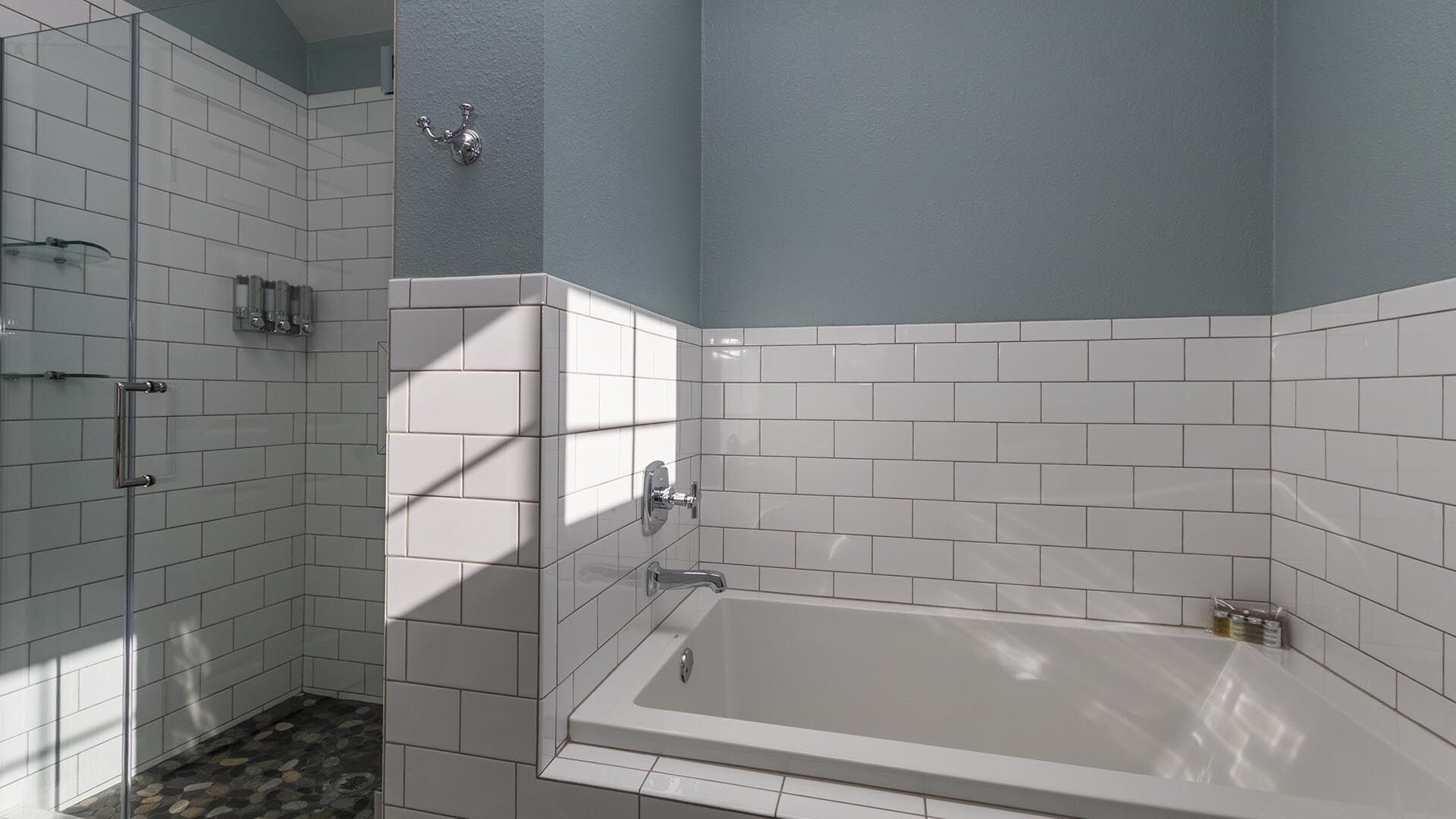 Une salle de bain équipée d’une baignoire, d’une douche et d’un espace de douche séparé par des parois en verre.