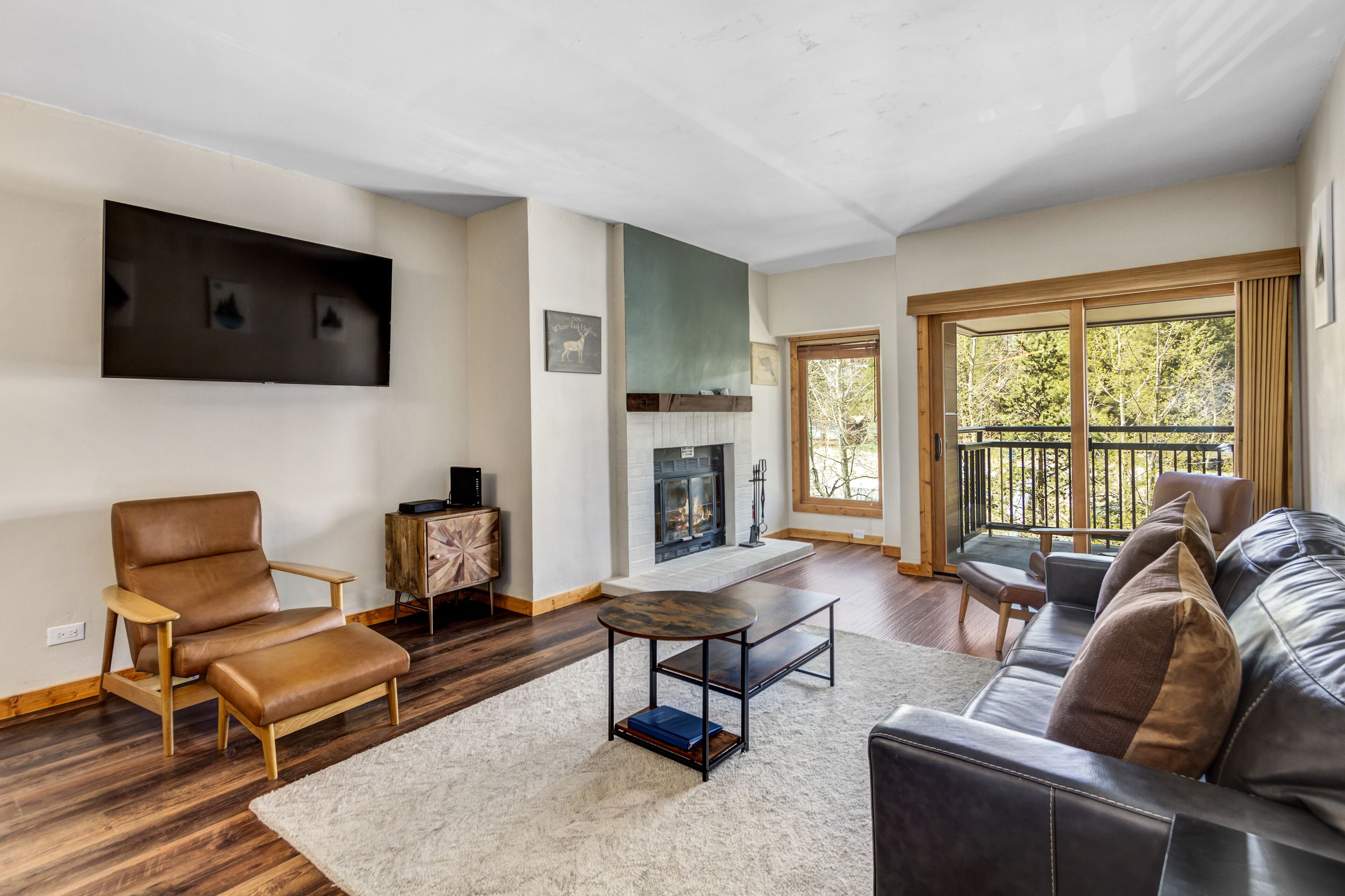 Una sala de estar con chimenea, muebles de cuero y un ventanal grande.