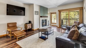 Una sala de estar con chimenea, muebles de cuero y un ventanal grande.