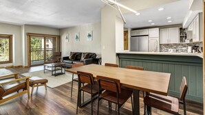 Una cocina amplia con electrodomésticos modernos, un comedor con mobiliario de madera y vistas al exterior a través de ventanas grandes.