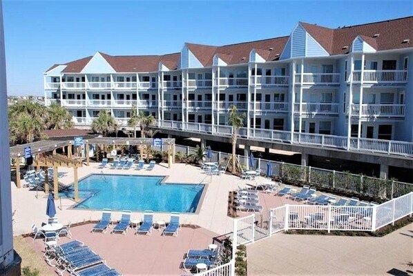 Un hotel con zona de piscina, varios balcones y un paseo cubierto.