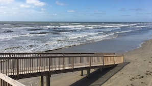 A wooden boardwalk leading to a beach with waves crashing onto the shore.