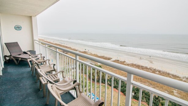 A balcony with beach views, featuring lounge chairs and a small table. - Direct Oceanfront 3BR/2BA, Park on same level as condo (Myrtle Beach)