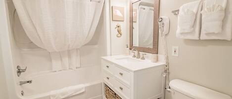 A bathroom with a bathtub, a sink, a toilet, and a mirror.
