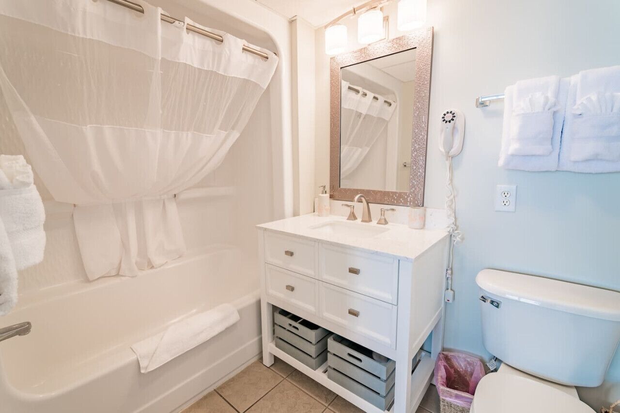 A bathroom with a bathtub, a sink, a toilet, and a mirror.