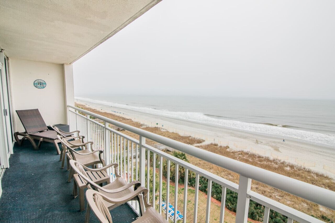 Un balcon avec des fauteuils de jardin donnant sur une plage.