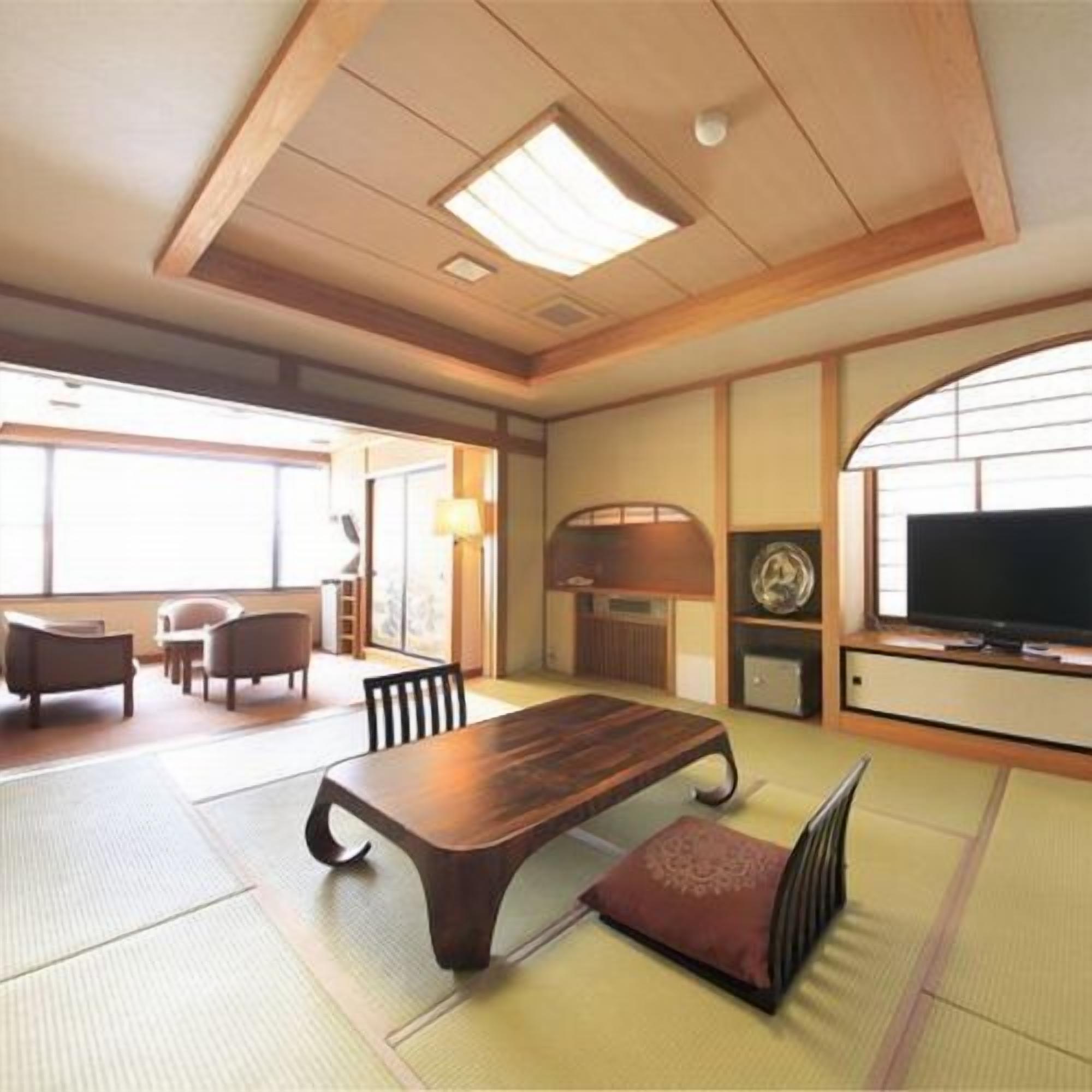 A traditional Japanese-style room with tatami flooring, a low wooden table, and a television.