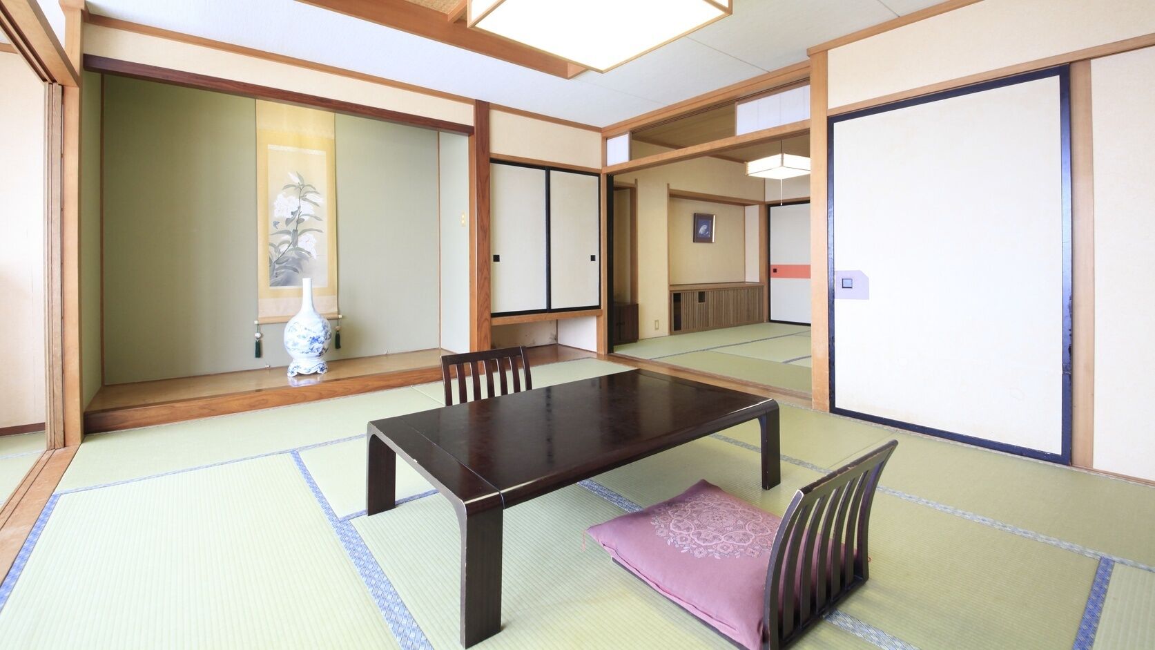 Um quarto japonês tradicional com tatames, uma mesa de madeira baixa e biombos shoji.