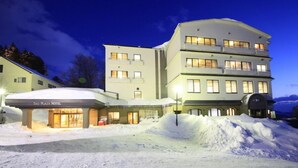 Un hôtel dont l’entrée est recouverte de neige, avec de nombreux étages et une architecture moderne.