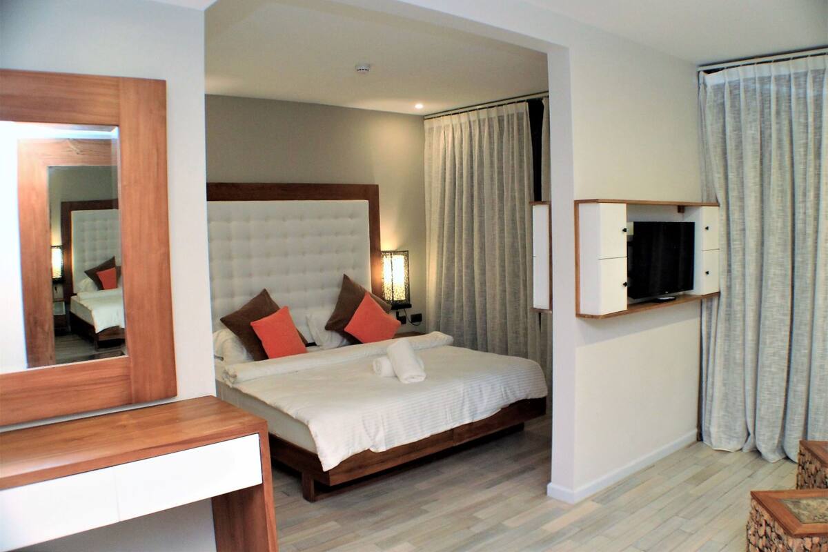 A hotel room with a large bed, a TV mounted on the wall, and a wooden desk.