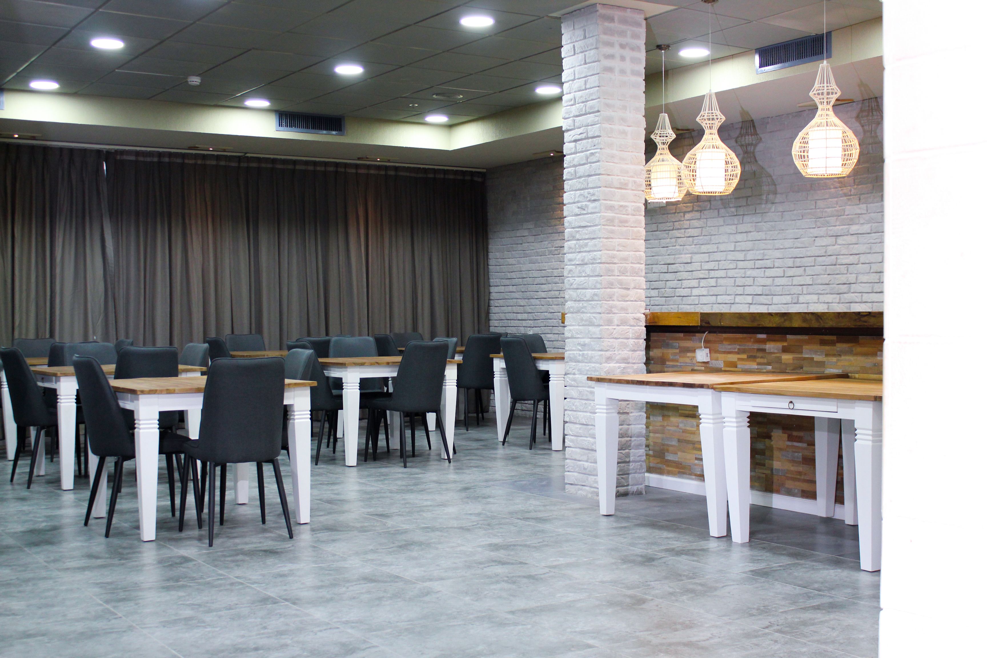 Ein Restaurant mit mehreren Tischen und Stühlen, einer Ziegelwand als Blickfang und hängenden Pendelleuchten.