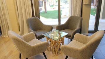Une pièce comprenant deux fauteuils beiges et une table avec un plateau en verre et des pieds en bois.