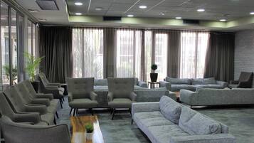 Un vestíbulo amplio con sofás grises, sillones y una mesa de centro de madera.