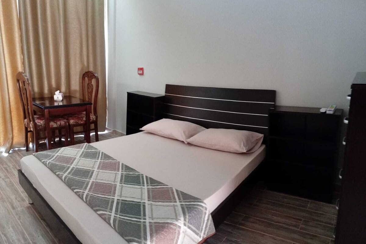 A neatly arranged hotel room with a bed, bedside tables, a small desk, and a chair.