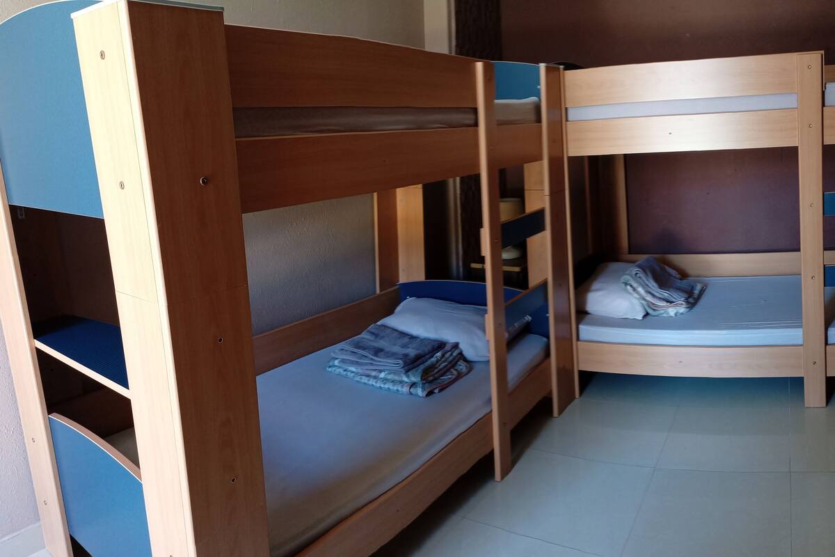 A room with bunk beds, a small desk, and a cabinet.