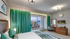 Habitación de hotel con cama, escritorio, silla, cómoda y vista a la ciudad.