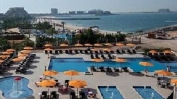 Un resort con varias piscinas, tumbonas y sombrillas.