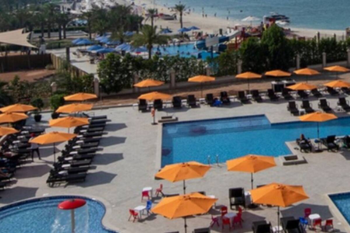 A resort pool area with multiple pools, sun loungers, and umbrellas.