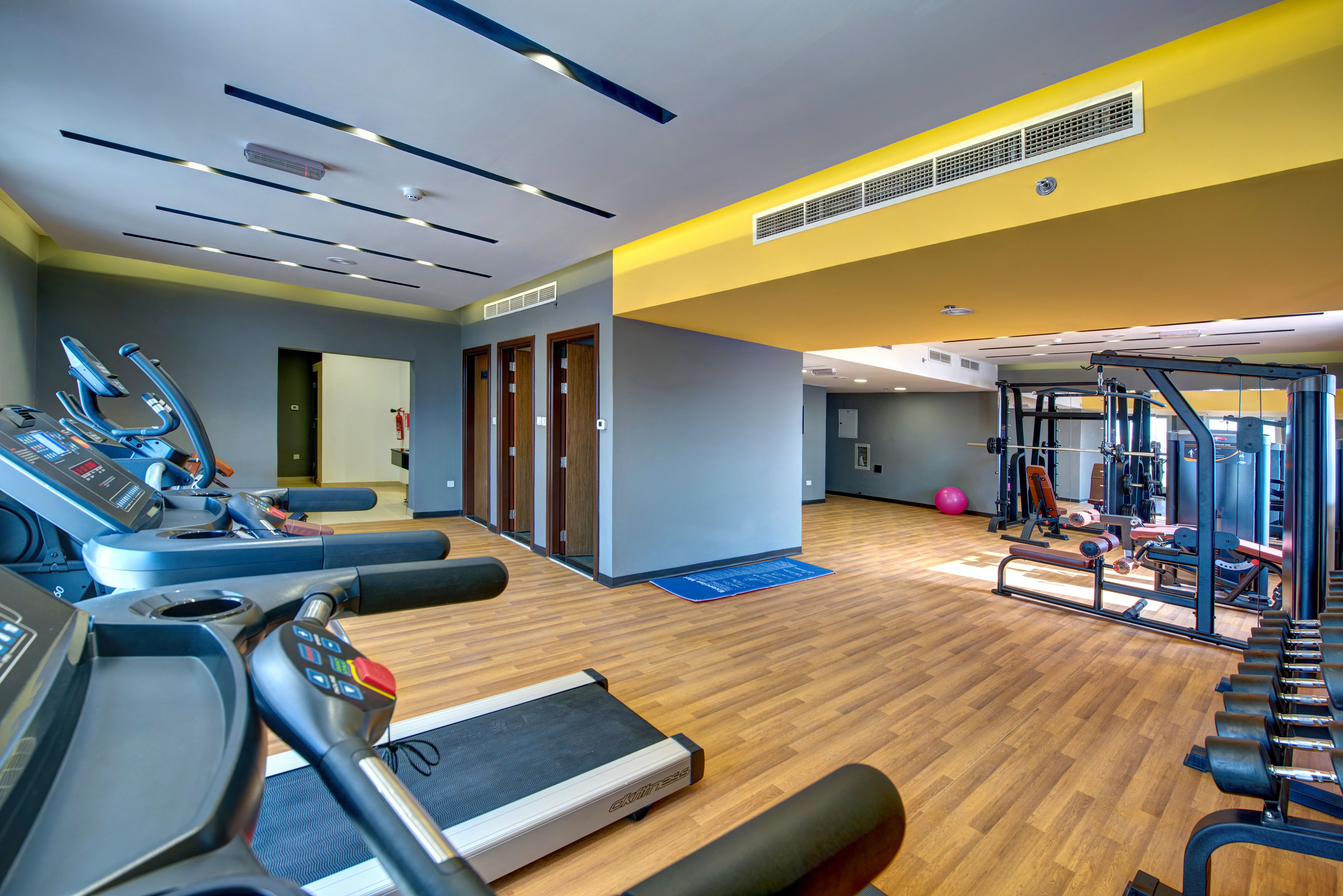 A gym with treadmills, a weight bench, and exercise equipment.