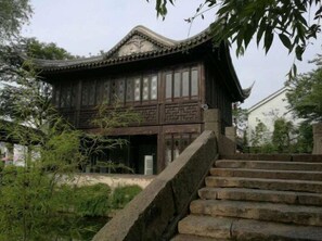 Un bâtiment traditionnel en bois, doté d’un toit en tuiles et d’un escalier en pierre menant à l’entrée.