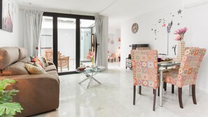 Un salon comprenant un canapé, une table basse en verre, des fauteuils à motifs et une table à manger.
