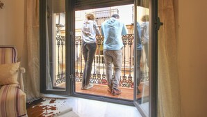 Une vue à travers une porte vitrée donnant sur un balcon doté d’une rambarde en métal.