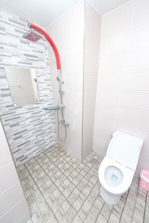Bathroom features a shower, toilet, and glass shelf.
