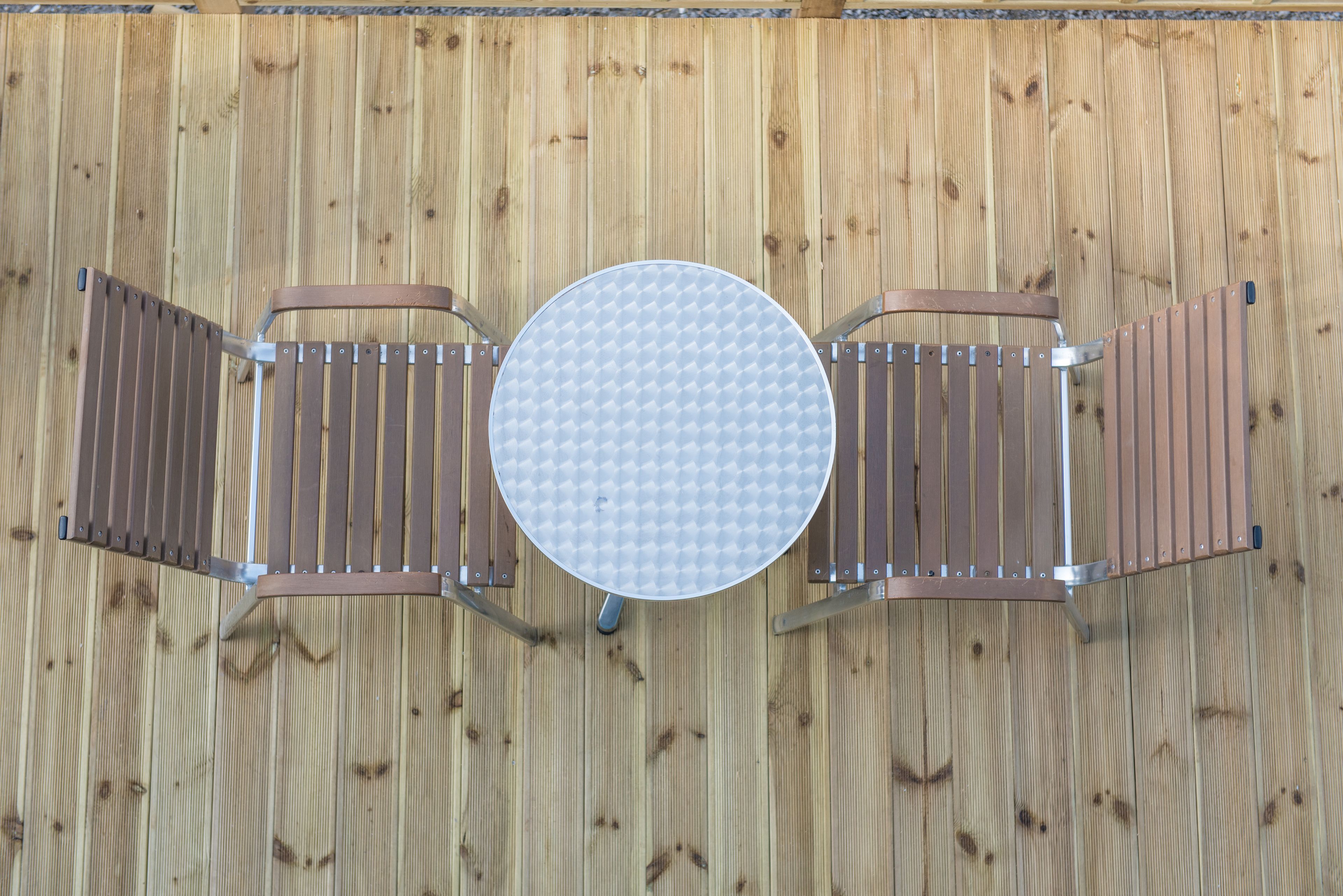 A round table with a white surface and four metal chairs with brown seats and backs.