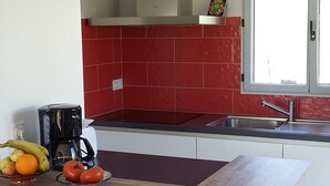 Eine moderne Küche mit roter Spritzschutzwand, einer integrierten Kochinsel, einer Kaffeemaschine und einem Fenster.