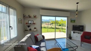 Ein Wohnzimmer mit einer Couch, roten Sesseln, einem Fernseher und einem Glastisch.