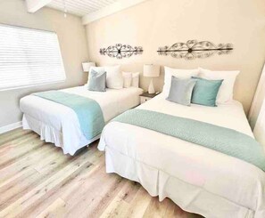 Een hotelkamer met twee bedden, een raam met zonwering en decoratieve wandkunst.