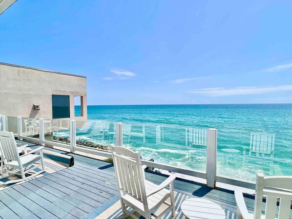 Een terras met witte stoelen met uitzicht op een heldere blauwe zee.