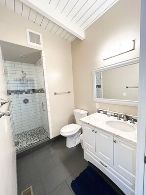 Een badkamer met een inloopdouche, toilet en wastafel met spiegel.
