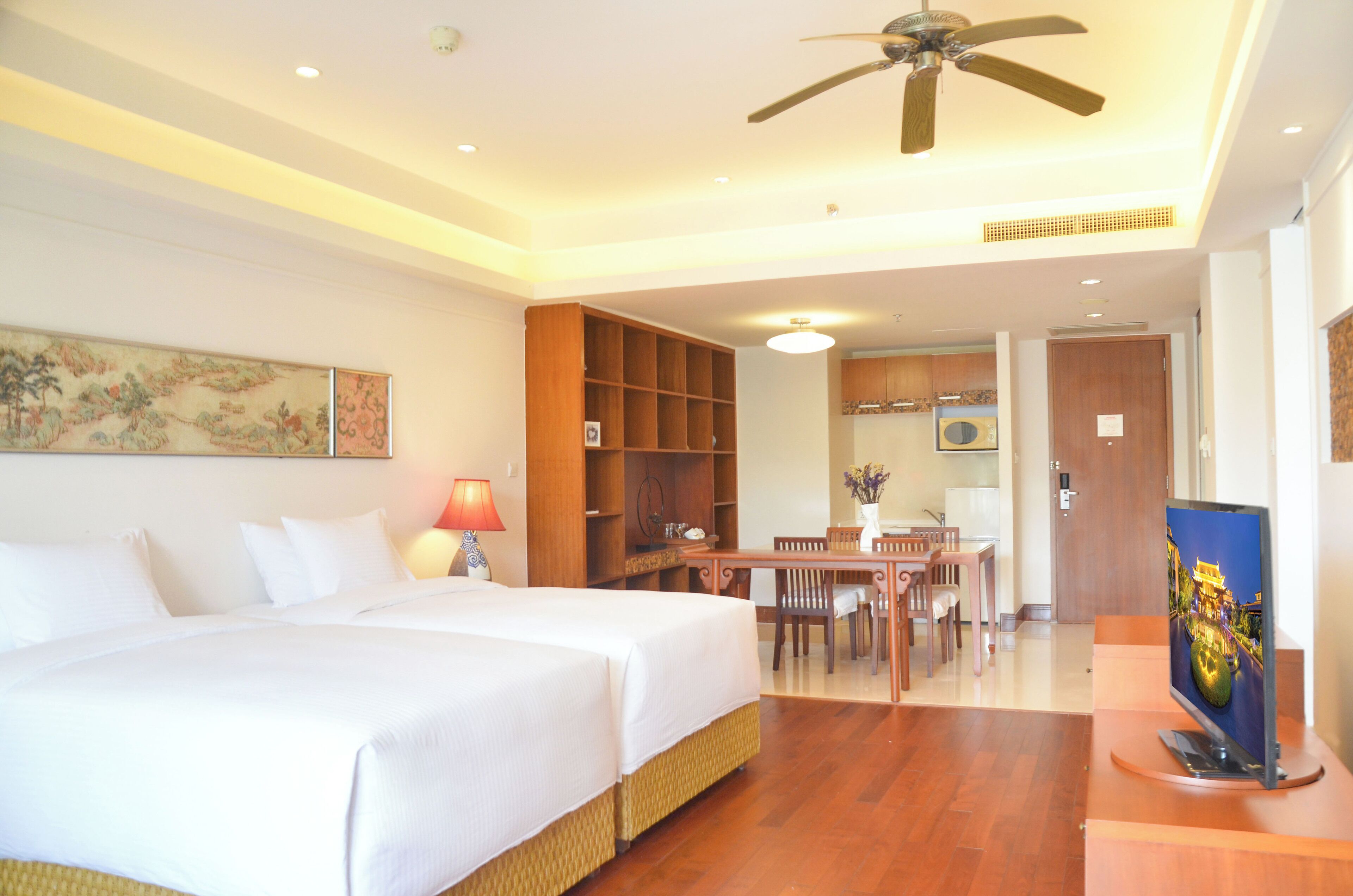 A hotel room with a bed, a desk, and a television.