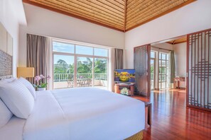 A spacious bedroom with a large bed, a balcony with a view of palm trees, and a traditional Asian-style room divider.