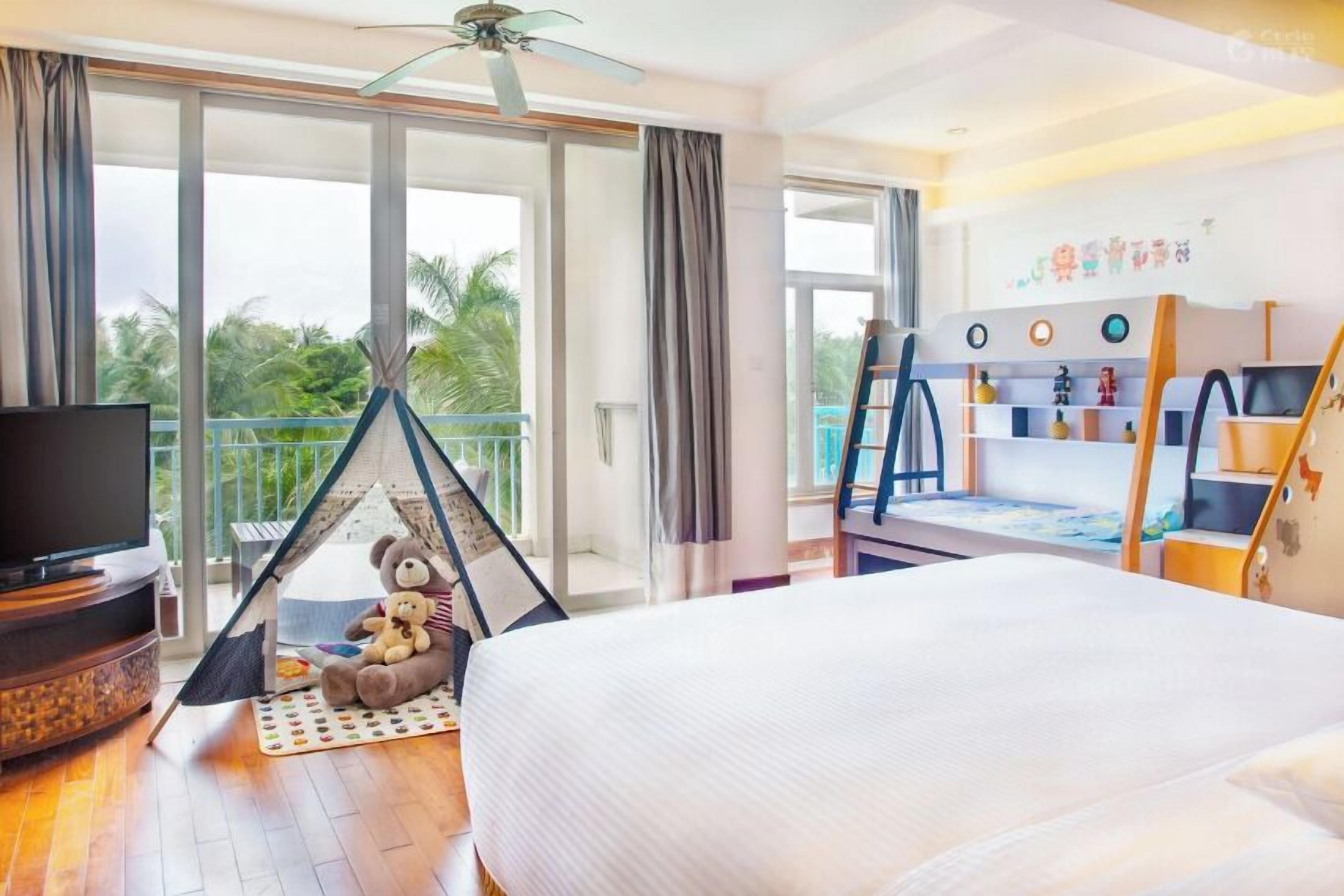 Een hotelkamer met een bed, een televisie, een tent en een balkon met uitzicht op palmbomen.