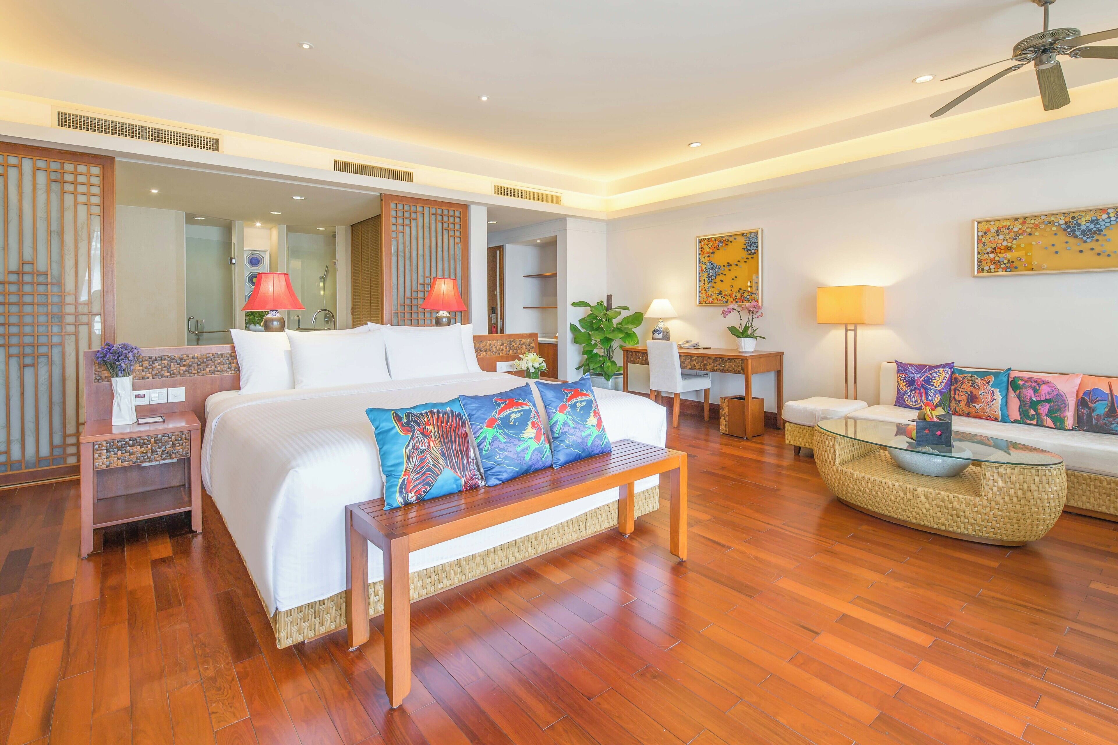 Une chambre d’hôtel moderne avec un grand lit, un banc en bois, une table basse en verre et un canapé.