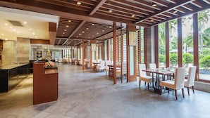 Een ruime binnenzone met een hoge plafond, grote ramen en een centraal zithoek met tafels en stoelen.