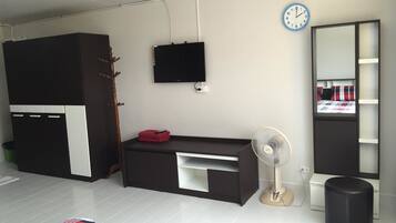 Un dormitorio moderno con un armario, televisor, ventilador, espejo y cama.